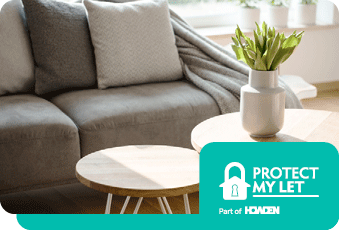 Sofa with cushions and a throw just behind a coffee tables with a vase and flowers on
