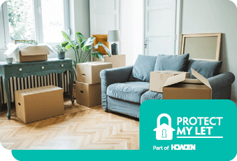 An unoccupied room which has a sofa, table, plant, lamp and several boxes